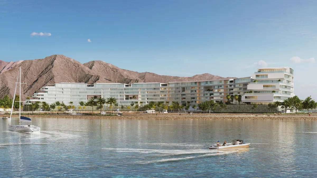 The Arc seen along the bay, a single continuous curve set against the Hajar mountains